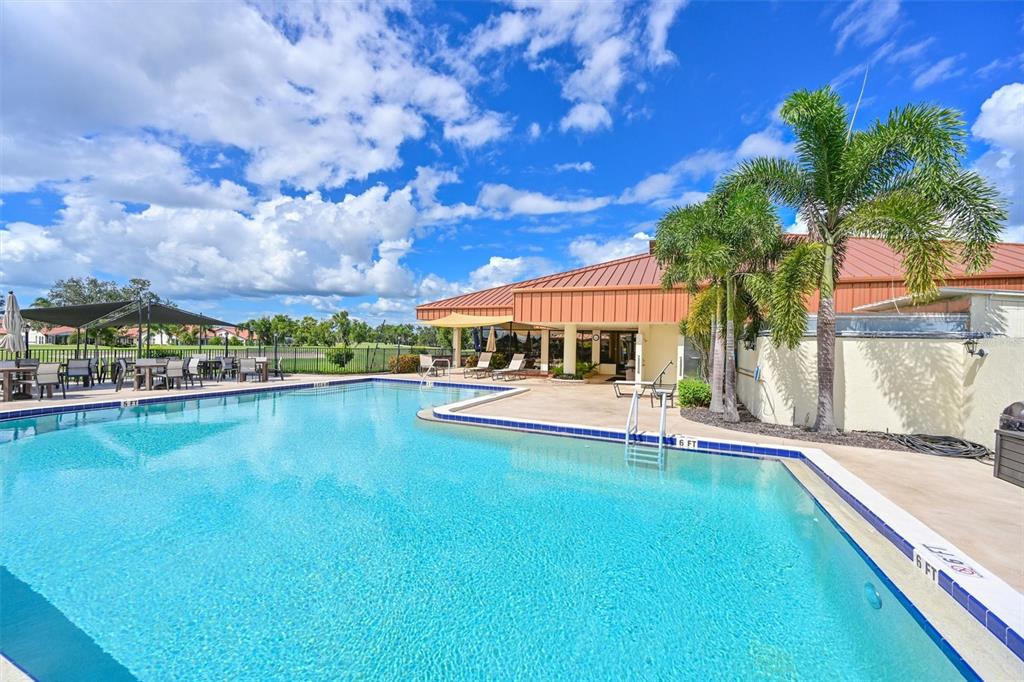 A swimming pool with a depth marker sits in front of a building with palm trees — 4427 MURFIELD DRIVE E, BRADENTON, FL