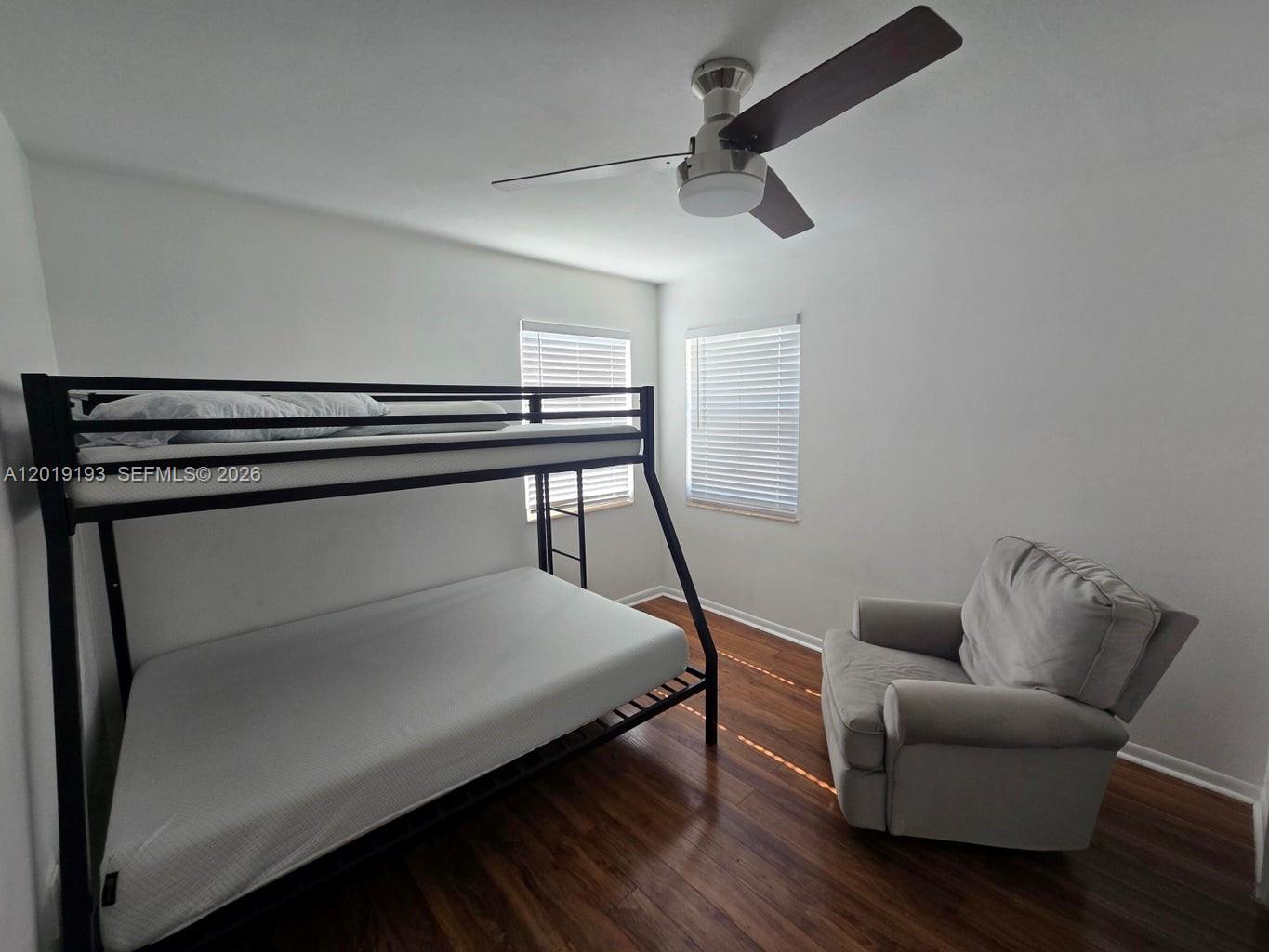 A bedroom features a black metal bunk bed, a gray armchair, and wood-look flooring — 37 Orange Dr, Key Largo FL 33037, KEY LARGO, FL