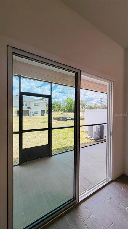A sliding glass door opens to a screened-in patio overlooking a grassy backyard and house — 3639 SE 37TH AVENUE, OCALA, FL