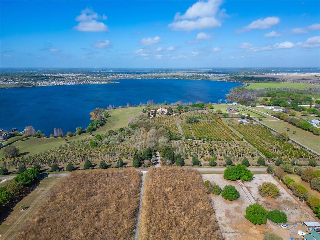 An aerial view shows a large waterfront property with agricultural fields and a house — ADAMS BARN ROAD, AUBURNDALE, FL