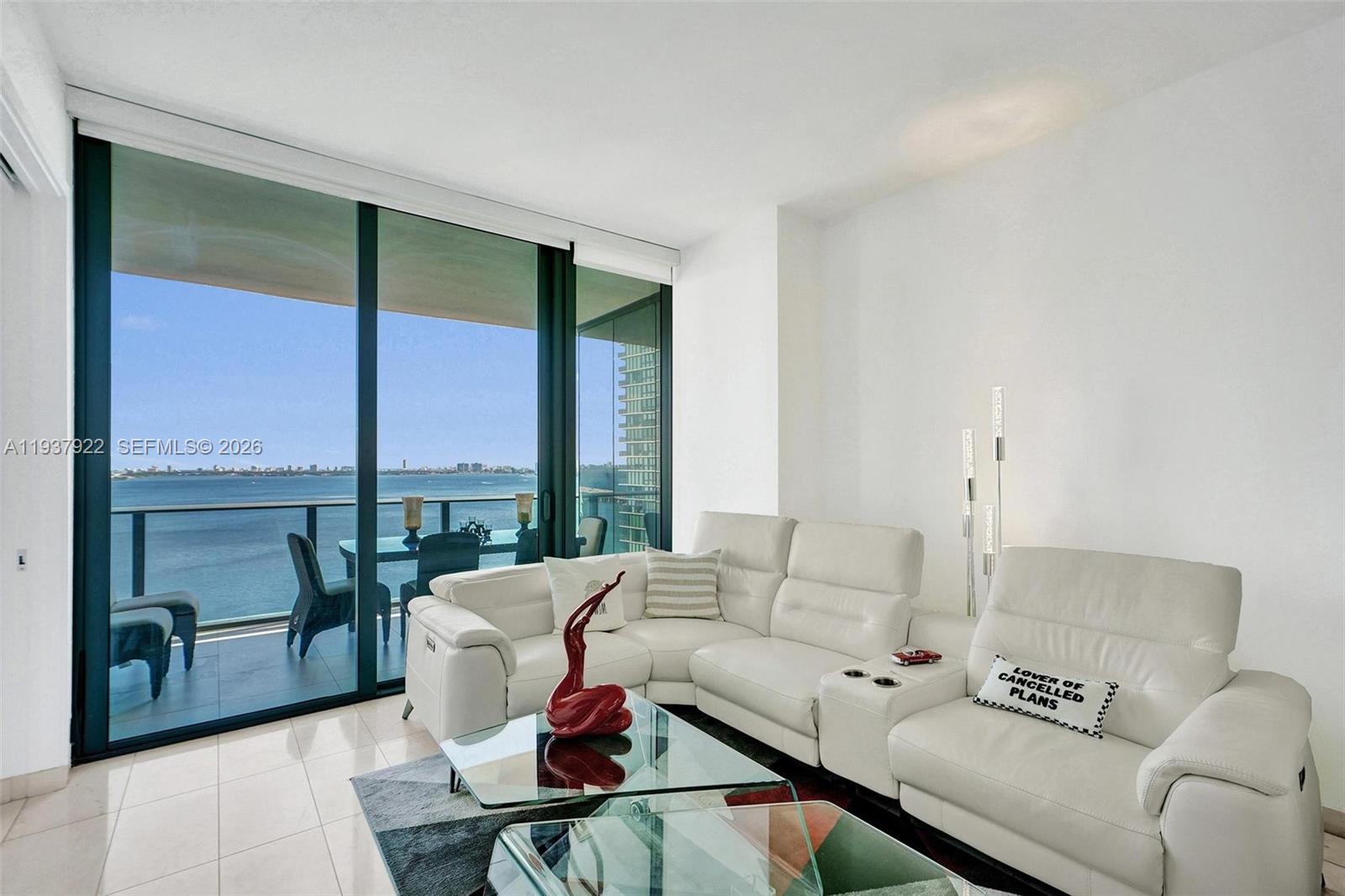 A white leather sectional sofa sits in a living room with floor-to-ceiling windows overlooking water — 480 NE 31st St # 1705, Miami FL 33137, MIAMI, FL