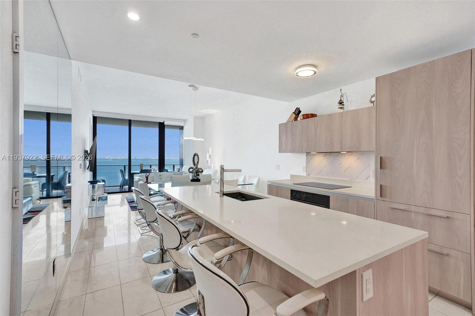 A modern kitchen features a long white island, light wood cabinetry, and a balcony view — 480 NE 31st St # 1705, Miami FL 33137, MIAMI, FL