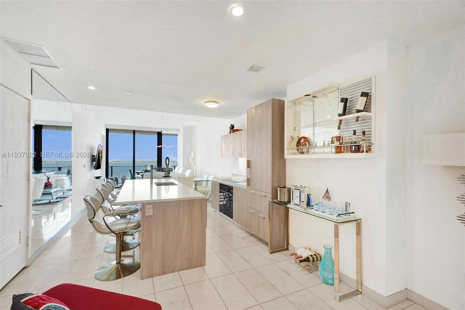 A modern kitchen features a light wood island, bar seating, and a built-in wine rack — 480 NE 31st St # 1705, Miami FL 33137, MIAMI, FL