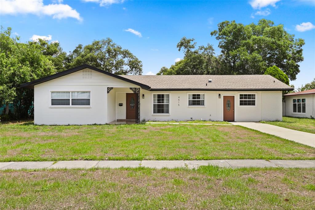 A single-story white house with two front doors and a brown shingled roof — 4515 BRADLEY AVENUE, ORLANDO, FL