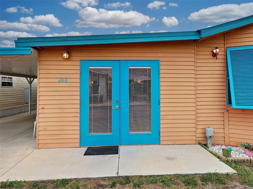 The exterior of a tan mobile home features bright blue double doors and trim — 1475 FLAMINGO DRIVE UNIT 286, ENGLEWOOD, FL