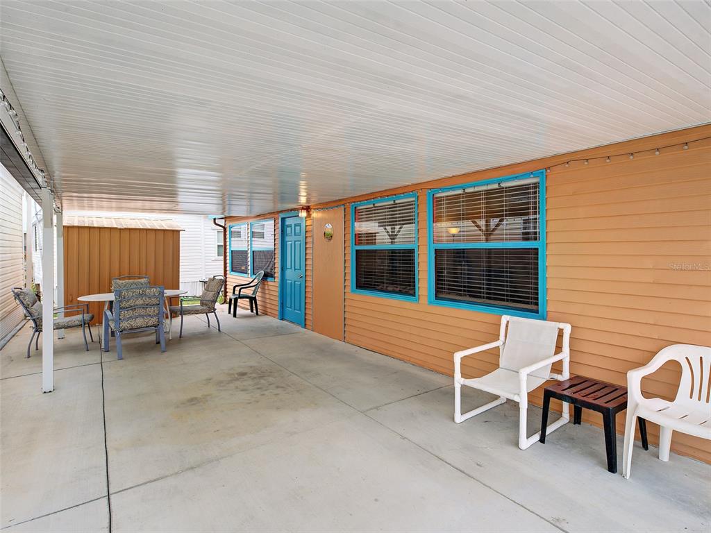A covered concrete patio features orange siding, blue window trim, and outdoor furniture — 1475 FLAMINGO DRIVE UNIT 286, ENGLEWOOD, FL