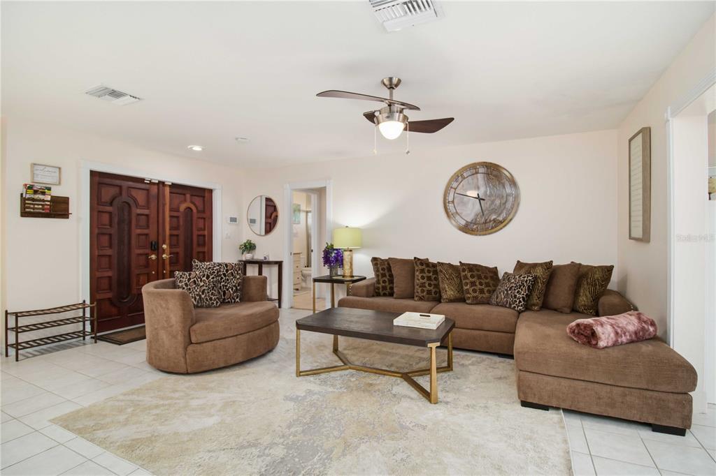 A living room features a brown sectional sofa, a matching armchair, and a large wall clock — 3136 BISPHAM ROAD, SARASOTA, FL