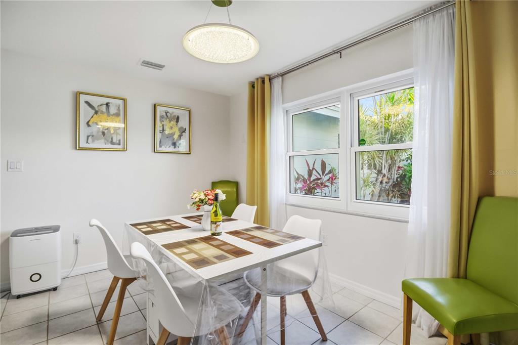 A dining room features a white table, four chairs, yellow curtains, and a modern light fixture — 3136 BISPHAM ROAD, SARASOTA, FL