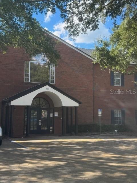 A two-story brick building features a prominent covered entrance and a paved parking lot — 1920 BOOTHE CIRCLE, LONGWOOD, FL