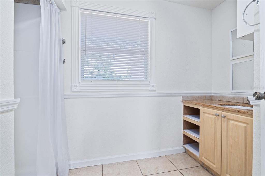 A bathroom features a shower, a window with blinds, and a vanity with open shelving — 3005 W KATHLEEN STREET, TAMPA, FL