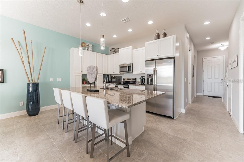A kitchen with white cabinets, granite countertops, a center island with bar stools, and tile flooring — 490 CAPTIVA DRIVE, DAVENPORT, FL