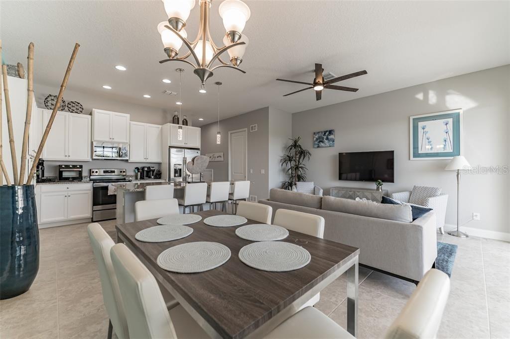 An open-concept kitchen, dining area, and living room featuring white cabinetry and neutral furniture — 490 CAPTIVA DRIVE, DAVENPORT, FL