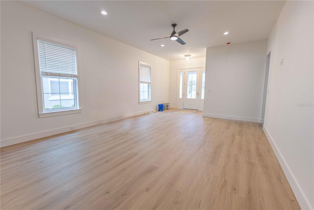 An empty living room features light wood-look flooring, white walls, recessed lighting, and a ceiling fan — 10619 GRAND OAKS BOULEVARD, OXFORD, FL