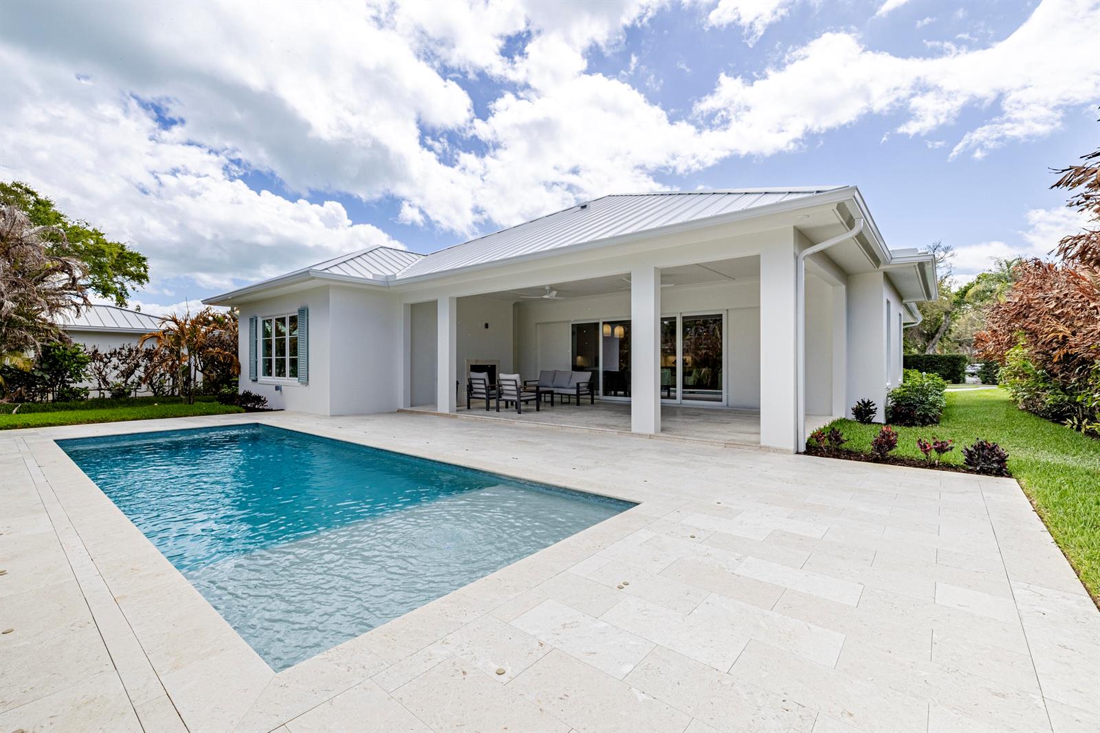 A white house with a metal roof features a covered patio and a swimming pool — 775 Acacia Road, Vero Beach FL 32963, VERO BEACH, FL