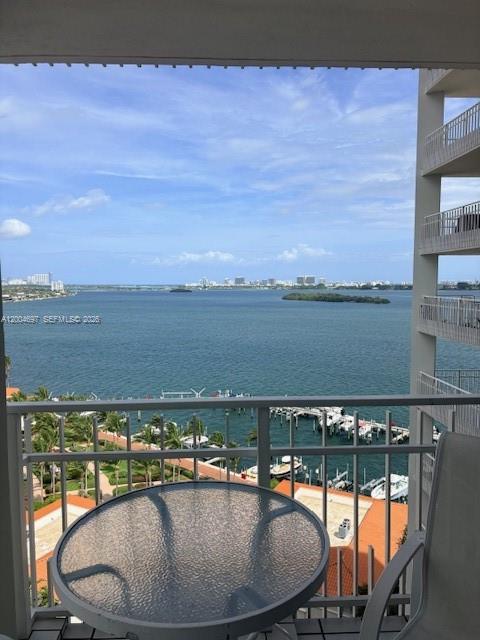 A balcony with a glass table overlooks a bay with a marina and distant city skyline — 4000 Towerside Ter # 1403, Miami FL 33138, MIAMI, FL