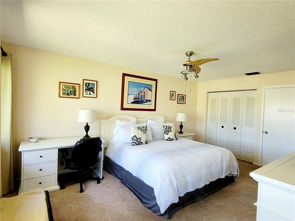 A bedroom features a bed, a desk with a chair, and white closet doors — 5147 WILLOW LINKS UNIT 18, SARASOTA, FL