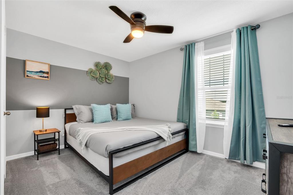 A bedroom features a bed with a metal frame, gray bedding, and teal curtains — 2131 DERWENT DRIVE, DAVENPORT, FL