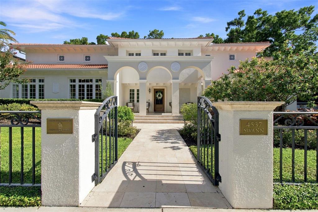 A gated walkway leads to the arched entryway of a Mediterranean-style house with a tile roof — 4537 W SWANN AVENUE, TAMPA, FL