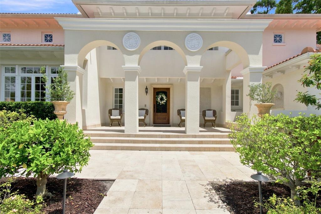 The exterior of a light-colored home features a covered entryway with arched columns and steps — 4537 W SWANN AVENUE, TAMPA, FL