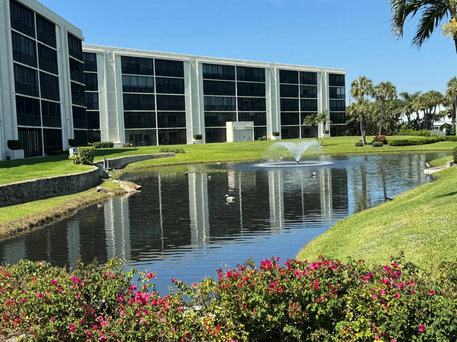 A multi-story apartment building overlooks a pond with a fountain and landscaped grounds — 200 Intracoastal Place # 404, Jupiter FL 33469, JUPITER, FL