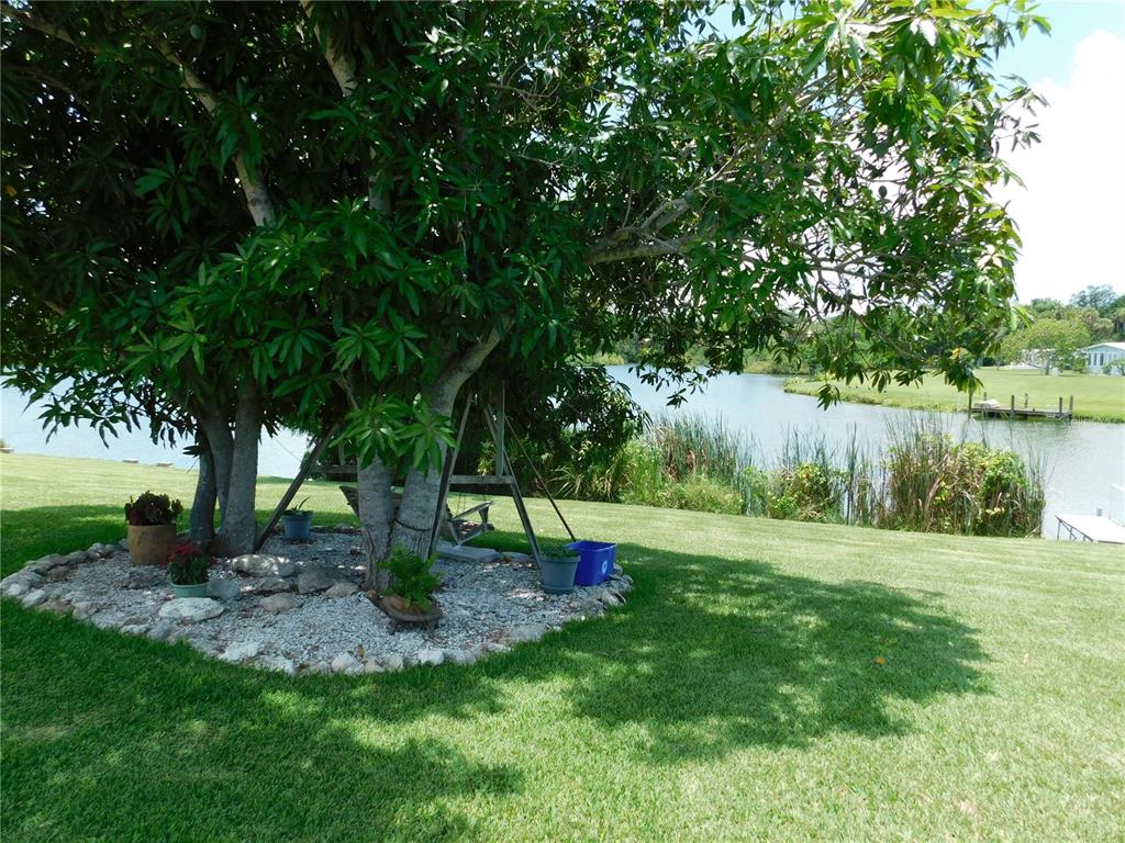 A house exterior features a covered patio, two red doors, and a view of water — 4619 15TH STREET COURT E, ELLENTON, FL