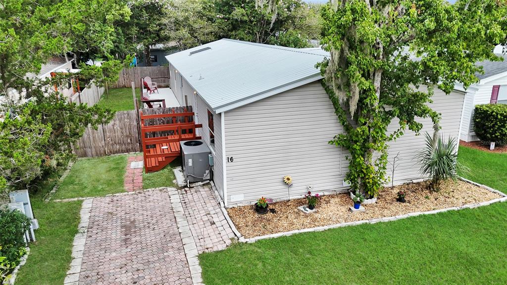 An aerial view of a single-story house with light siding, a metal roof, and a driveway — 16 CAYMAN CIRCLE, UMATILLA, FL