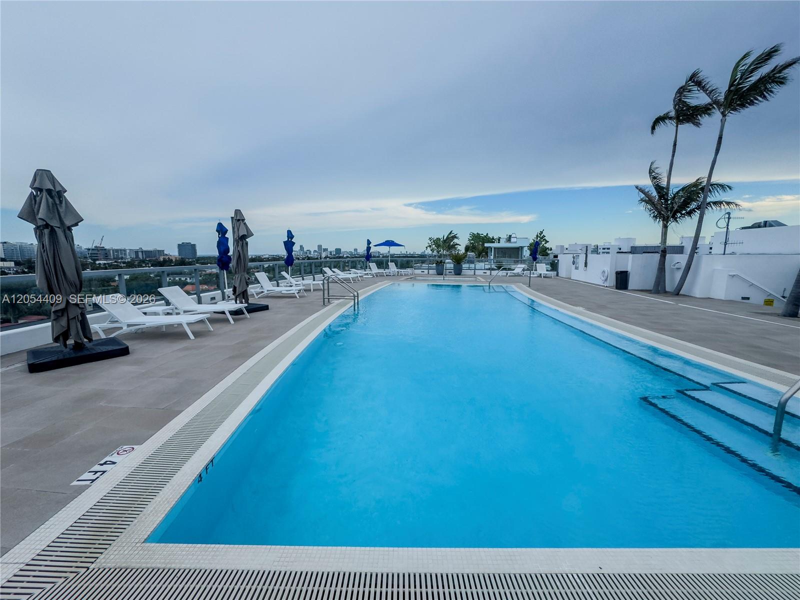 A rooftop swimming pool features lounge chairs, umbrellas, and a view of the city skyline — 9261 E Bay Harbor Dr # 405, Bay Harbor Islands FL 33154, BAY HARBOR ISLANDS, FL