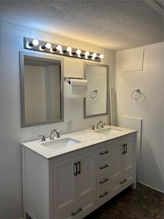 A bathroom features a double vanity with white cabinets, quartz countertops, and two framed mirrors — 8456 SW STATE ROAD 47, LAKE CITY, FL
