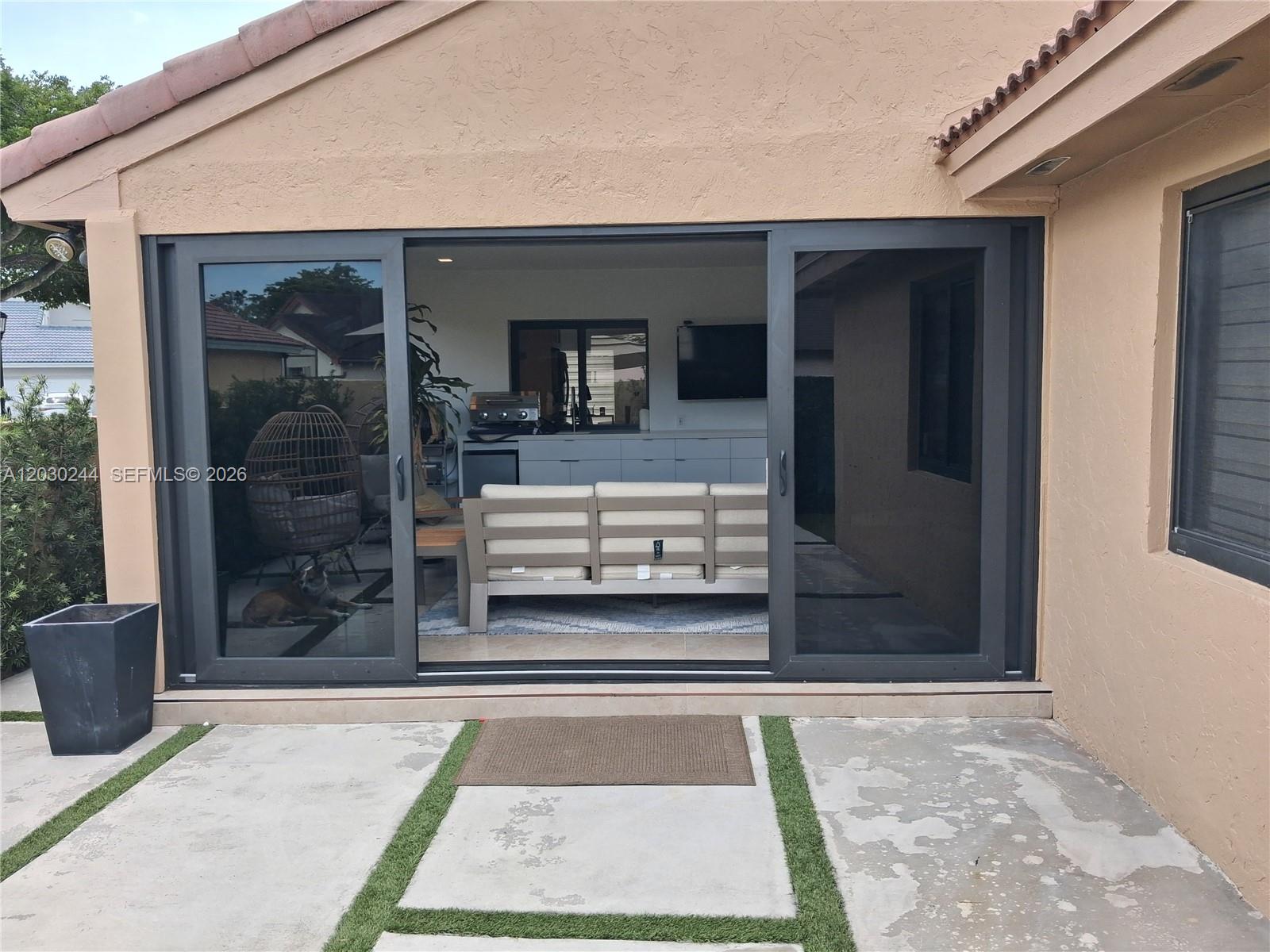 A sliding glass door opens from a concrete patio into a furnished indoor living space — 17531 NW 62nd Pl N, Hialeah FL 33015, HIALEAH, FL