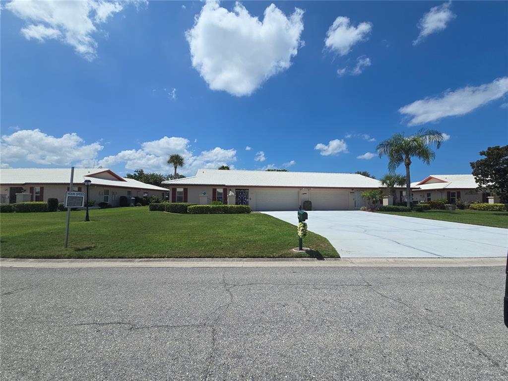 A single-story duplex with white roofs, beige siding, and a large shared concrete driveway — 6601 11TH AVENUE W UNIT 6003, BRADENTON, FL