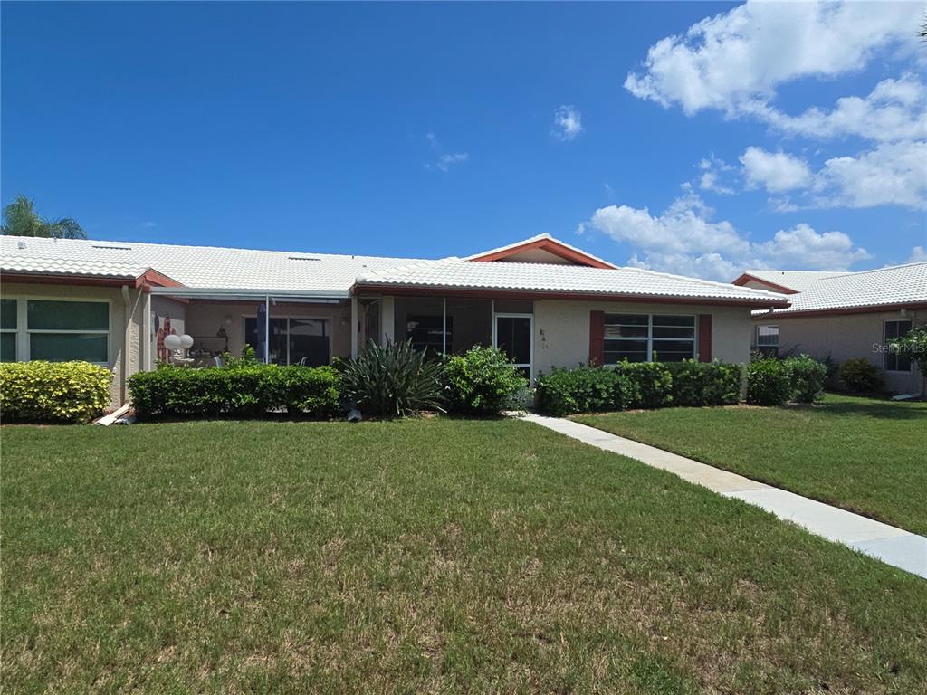 A single-story house with a white tile roof, light-colored exterior, and a manicured front lawn — 6601 11TH AVENUE W UNIT 6003, BRADENTON, FL
