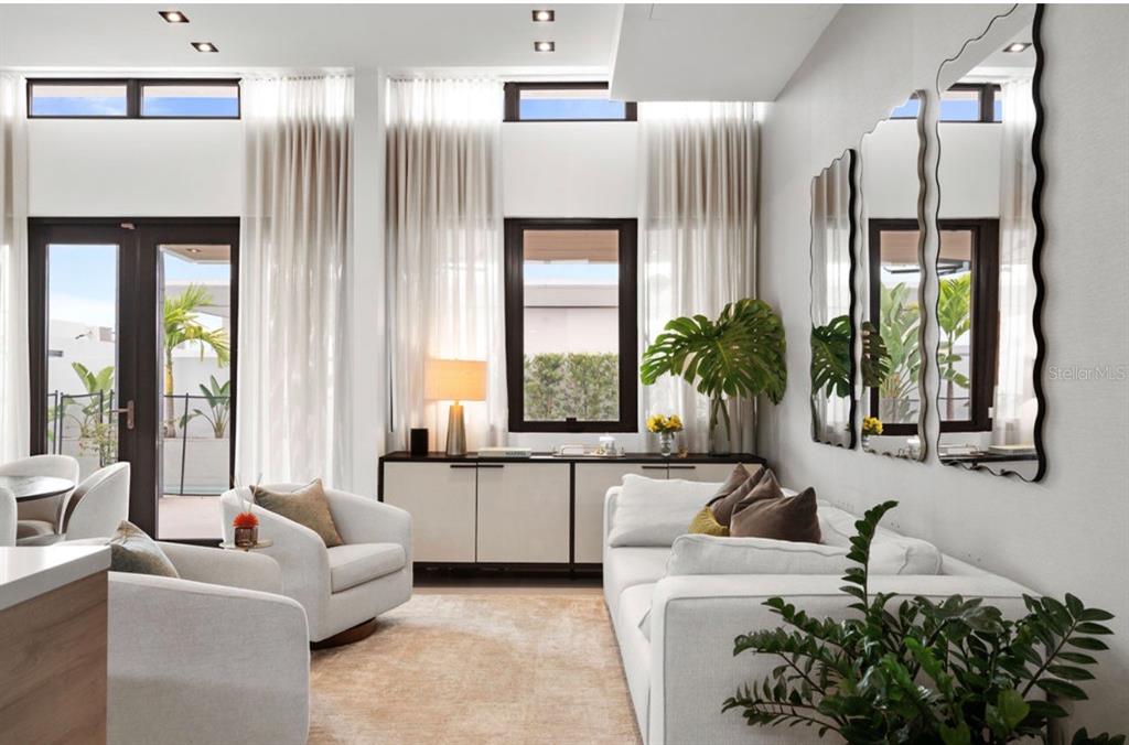 A modern living room features white furniture, tall windows with curtains, and wavy wall mirrors — Ebro 68, BAYAMON, PR
