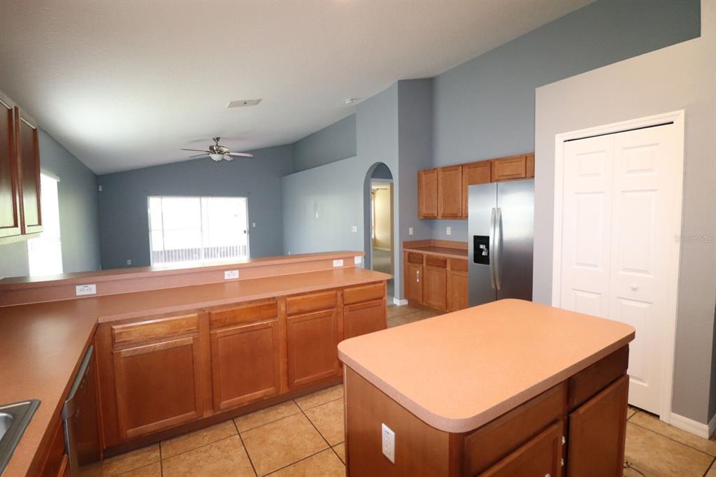 A kitchen with wood cabinets, laminate countertops, a center island, and tile flooring — 324 RED KITE DRIVE, GROVELAND, FL