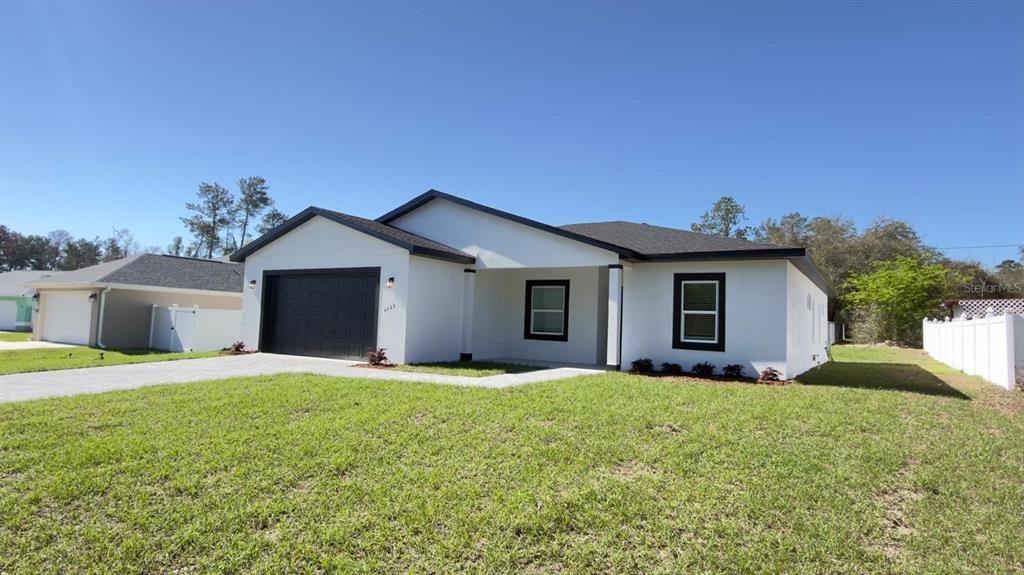 A single-story house with a white exterior, black trim, and a dark garage door — 4522 SW 170TH STREET ROAD, OCALA, FL
