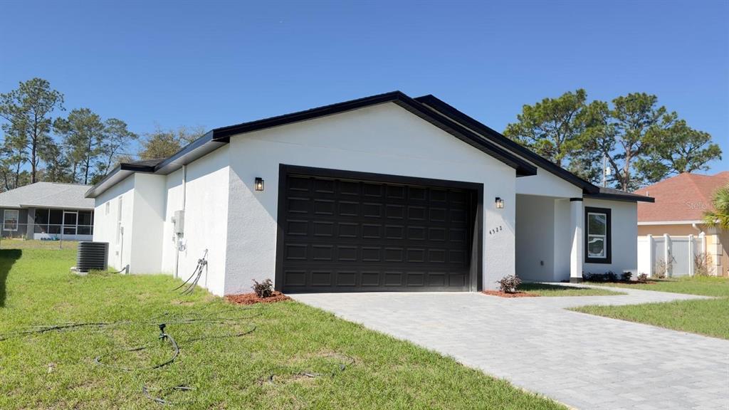 A white single-story house with a black garage door and a paved driveway — 4522 SW 170TH STREET ROAD, OCALA, FL