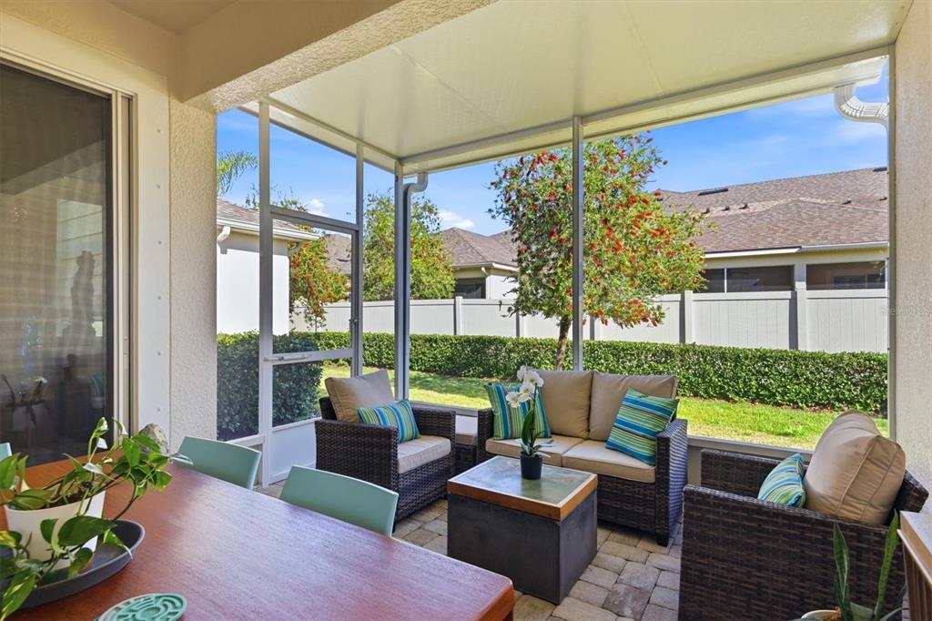 A screened-in patio features wicker furniture, a dining table, and a view of a backyard — 3684 FESCUE LANE, SARASOTA, FL