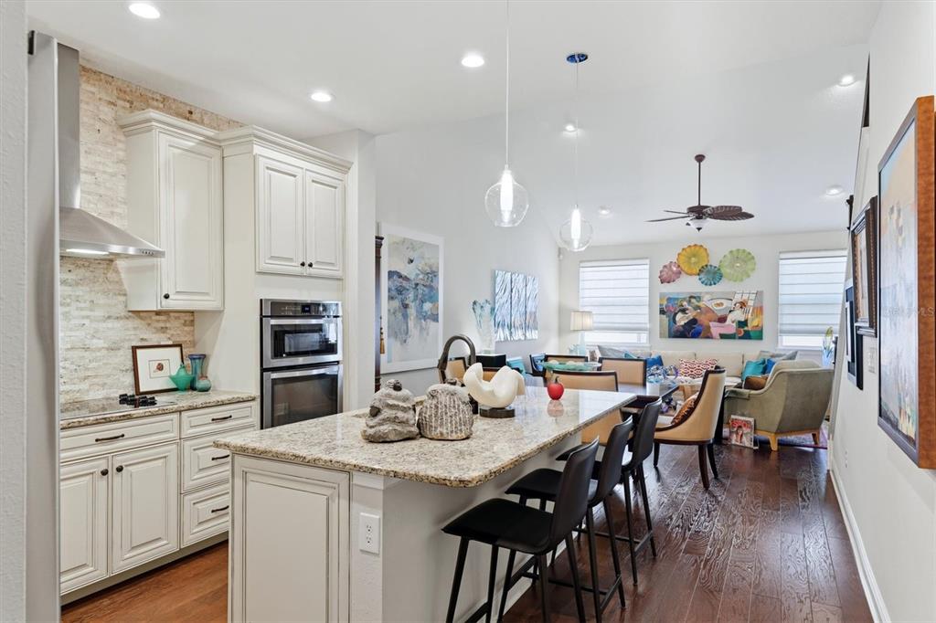 A kitchen with a granite island and white cabinets opens into a living area — 3684 FESCUE LANE, SARASOTA, FL