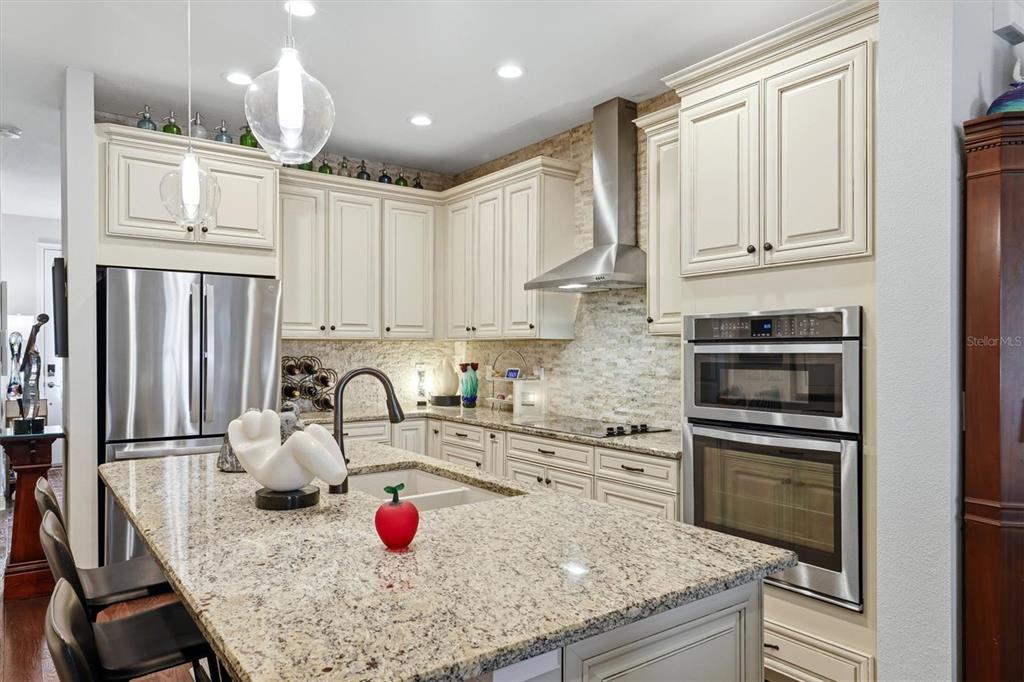 A kitchen features cream cabinets, granite countertops, stainless steel appliances, and a central island — 3684 FESCUE LANE, SARASOTA, FL