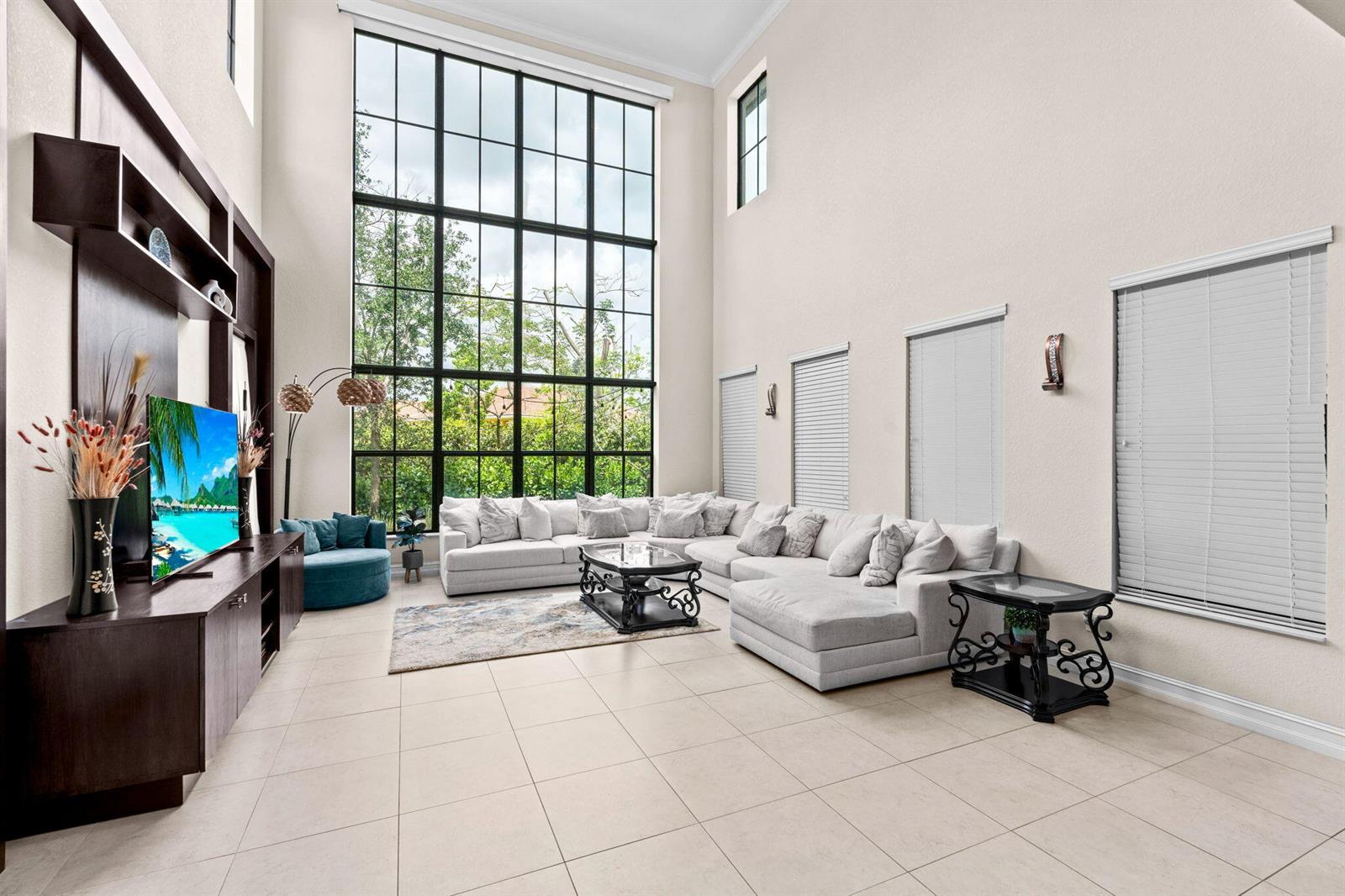 A living room features a large sectional sofa, a tall window wall, and tile flooring — 8845 WATERCREST Circle W, Parkland FL 33076, PARKLAND, FL