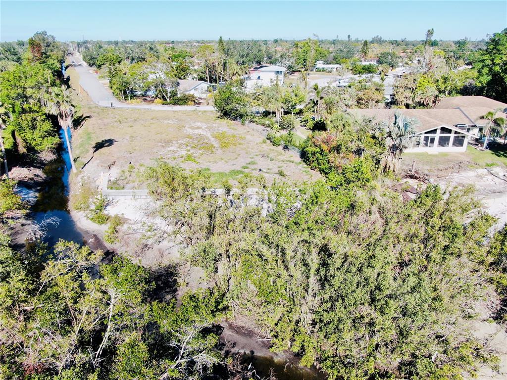 An aerial view shows a vacant lot bordered by a canal and residential houses — 6649 RENSSALAER DRIVE, BRADENTON, FL
