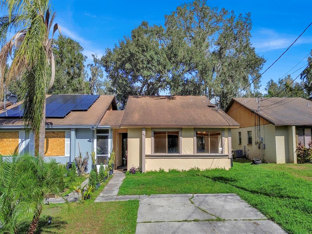 A single-story house with a tan exterior, a concrete driveway, and a large tree behind it — 1057 OLD SOUTH DRIVE, LAKELAND, FL