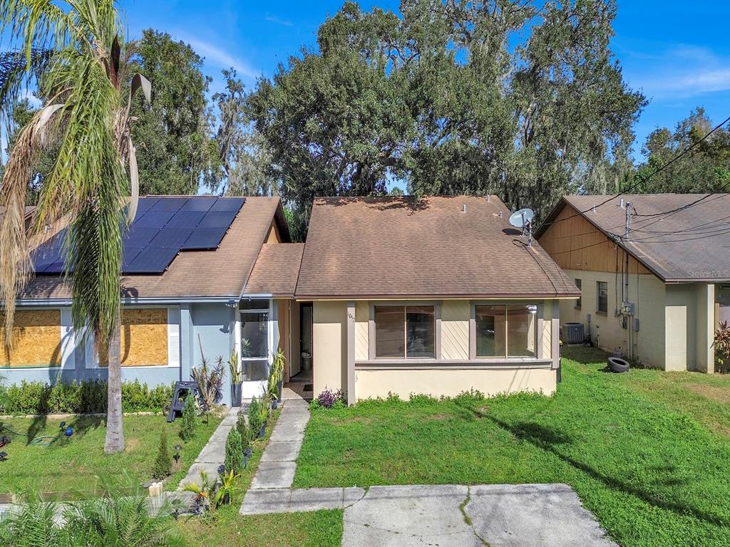 A single-story house with solar panels on the roof and boarded-up windows on the left — 1057 OLD SOUTH DRIVE, LAKELAND, FL