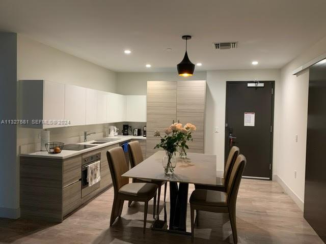 A modern kitchen features light wood cabinetry, a dining table with four chairs, and recessed lighting — 777 N Ocean Dr # S333, Hollywood FL 33019, HOLLYWOOD, FL