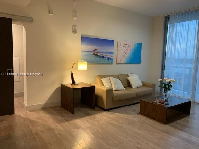 A living room features a beige sofa, a wooden side table with a lamp, and artwork — 777 N Ocean Dr # S333, Hollywood FL 33019, HOLLYWOOD, FL