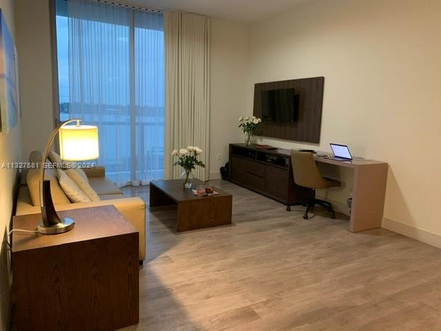 A living room features a sofa, coffee table, desk, and floor-to-ceiling window curtains — 777 N Ocean Dr # S333, Hollywood FL 33019, HOLLYWOOD, FL