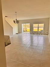 An open-concept living area features light-colored tile flooring, a chandelier, and sliding glass doors — 9282 WESTSIDE HILLS DRIVE, DAVENPORT, FL