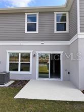 The rear exterior of a two-story house features a concrete patio and sliding glass doors — 9282 WESTSIDE HILLS DRIVE, DAVENPORT, FL