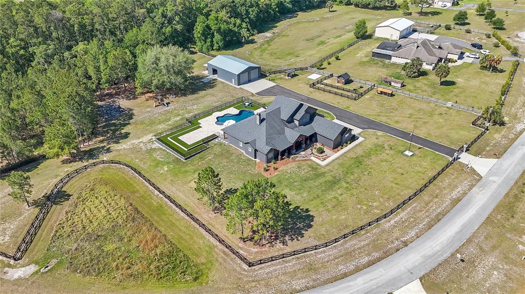An aerial view shows a house with a pool, detached garage, and fenced acreage — 22250 DEER PARK AVENUE, EUSTIS, FL