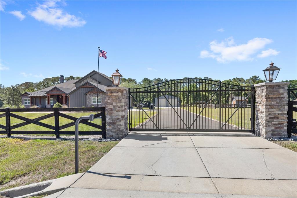A paved driveway leads to a gated entrance with stone pillars and a wooden fence — 22250 DEER PARK AVENUE, EUSTIS, FL