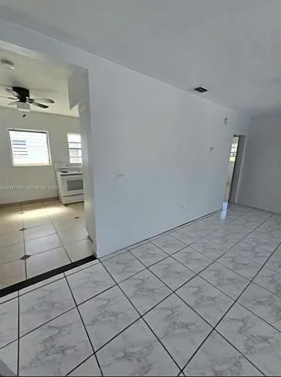 A tiled living area opens into a kitchen featuring a white stove and ceiling fan — 1420 NE 171st St # 2, North Miami Beach FL 33162, NORTH MIAMI BEACH, FL